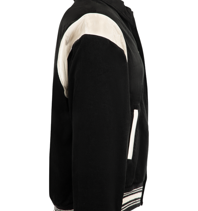 Image 3 of 3 - BLACK - SAINT Mxxxxxx Men's Corduroy Varsity Jacket is crafted from cotton corduroy and features a classic varsity-inspired silhouette with a pointed collar, snap-button front closure, and contrast shoulder panels. Designed with welt pockets, striped rib-knit cuffs and hem, and vintage collegiate influences, this statement jacket blends heritage sportswear styling with SAINT Mxxxxxx's contemporary streetwear aesthetic. Main Material: Cotton Corduroy. Made in Japan. 