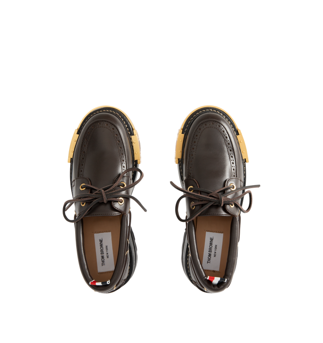 Image 4 of 4 - BROWN - THOM BROWNE Vitello Lug Boat Shoes featuring grained calfskin boat shoes, bumper hardware at toe with enameled stripes, perforated detailing at moc toe, lace-up closure, padded collar, serrated edge at sides and heel counter, tricolor grosgrain pull-loop at heel collar, buffed calfskin lining, stacked leather midsole and heel and treaded rubber sole. Heel: H2". Calfskin. Sole: rubber. Made in Italy. 