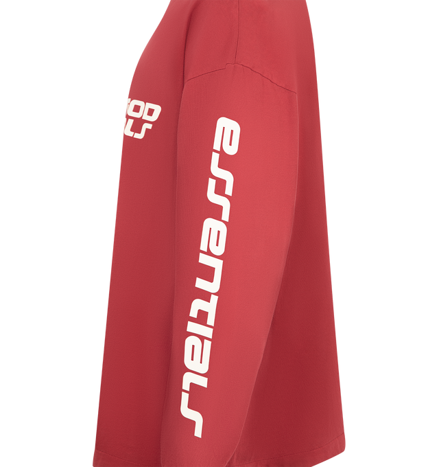 Image 3 of 3 - RED - Fear of God Essentials 90's Long Sleeve Tee is made from 100% cotton jersey, offering a soft yet substantial hand feel. Designed in an oversized 90s-inspired silhouette, it features exaggerated proportions with dropped shoulders for a relaxed drape that tapers to rib-knit cuffs. The front is defined by a HD print application of the Fear of God Essentials lockup alongside the Essentials logos on the sleeves. The signature rubberized Fear of God Essentials label at the collar.Fit Note: Si 