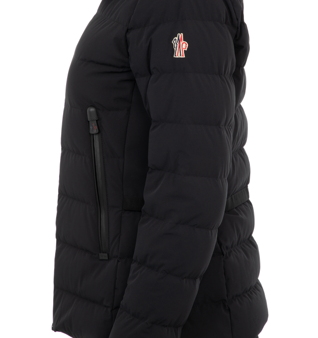 Image 3 of 3 - BLACK - Moncler Lamoura Hooded Shearling Jacket has an adjustable hood, detachable lambskin hood trim, a YKK AquaGuard 2-way zipper closure, exterior zipper pockets, wrist gaiters, an inner powder skirt, and a ski pass pocket. 84% polyamide, 16% nylon. Made in Romania.  