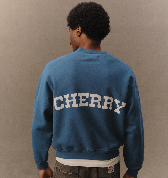 Image 7 of 7 - BLUE - Cherry LA Men's Patch Work Henley Crew is crafted from custom cotton fleece and features a boxy-fit silhouette with patchwork detailing at the chest and a concealed-button Henley placket. Designed for everyday comfort, this elevated sweatshirt is finished with hidden front buttons and a signature branded label at the cuff. Main Material: Custom Cotton Fleece. Made in Los Angeles, California. 