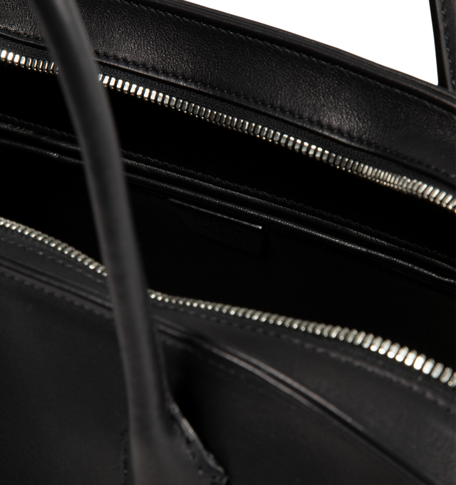 Image 3 of 3 - BLACK - The Row Agnes 15 Bag is crafted from a smooth calfskin leather and features a softly structured top-handle silhouette with tubular handles, gusseted side folds, a curved top zip closure, and a flat base. This designer leather handbag combines exceptional Italian craftsmanship with a spacious, minimalist design, while the naturally finished, metal-free tanned calfskin offers an exceptionally soft touch. Main Material: 100% Calfskin Leather. Lining: 100% Lambskin Leather. Dimensions: 17 