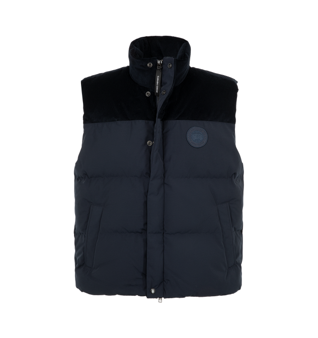Image 2 of 3 - NAVY - Canada Goose Men's Sterling Corduroy Puffer Vest is crafted from signature Recycled Organic Arctic Tech with breathable Italian cotton corduroy at the shoulders and collar. Designed for temperatures from 41F to 23F, it features a concealed snap placket over a two-way zipper, an adjustable drawcord hem, two exterior snap-welt pockets, and two interior pockets. Main Material: 100% Cotton. Fill: 90% Down, 10% Feathers.  