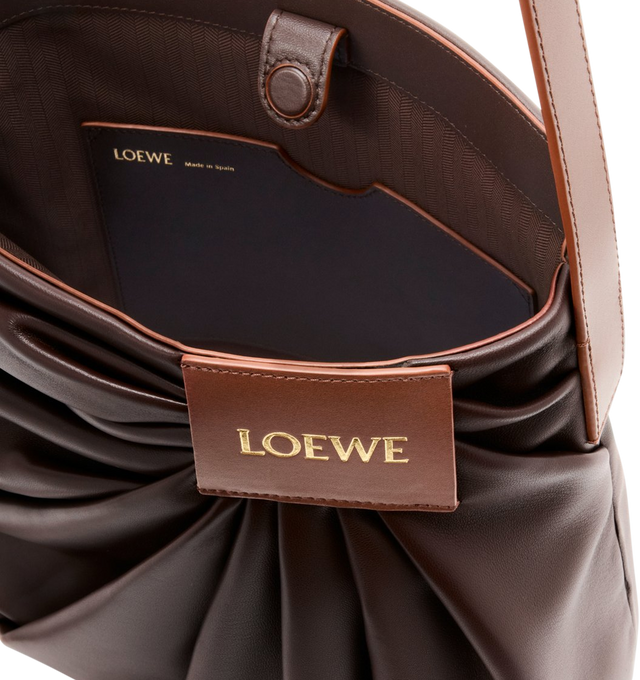 Image 4 of 4 - BROWN - LOEWE Draped Tote featuring soft scultpural shape and a wide strap adorned with a bold LOEWE-engraved buckle, shoulder or crossbody carry, adjustable strap, magnetic closure, one internal calfskin patch pocket, herringbone cotton canvas lining and gold embossed LOEWE. Mellow nappa lambskin. 30 cm x 29 cm x 13 cm. Made in Spain. This item may be restricted for online purchase to international clients. For assistance purchasing this item please contact our dedicated stylist team at pers 