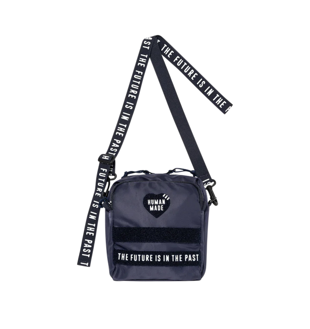 Image 2 of 4 - NAVY - Human Made vertical military pouch crafted from durable nylon. Adjustable, detachable shoulder strap allows it to be worn diagonally (cross-body). Removing the magic tape on the front reveals text, adding a playful touch. Features dual front 3D pockets featuring logo text and webbing loops, zip pocket at back, sleeve pocket at interior and zip closure at top. Measures 19 cm high x  17 cm wide x 5.5 cm deep. 100% nylon. Made in Japan. 