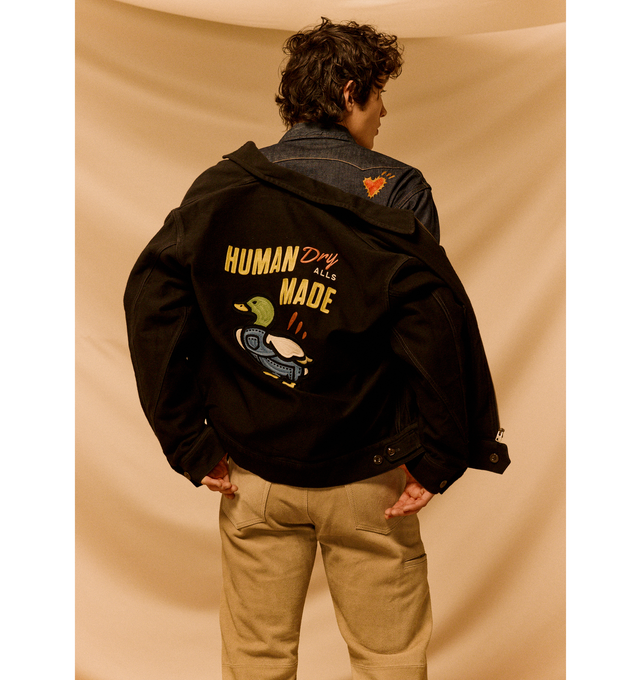 Image 2 of 3 - BLACK - HUMAN MADE Zip-Up Work Jacket featuring short length, thick cotton with a fine, textured striped pattern, two flap pockets on the front, duck graphic on the back, graphic expressed with chain stitching, brand logo on the left chest and drawcord with adjuster tabs with heart buttons. 100% cotton.  