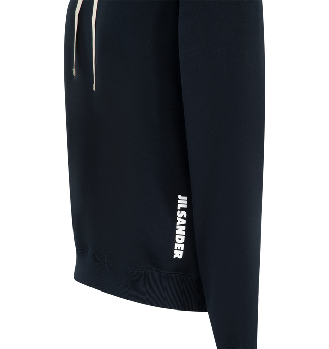 Image 3 of 3 - BLUE - Jil Sander Mens Logo Print Hoodie is crafted from cotton with a soft fleece lining. Features a relaxed fit, dropped shoulders, long sleeves, hood, ribbed cuffs, front contrast logo print, and embroidered headband accent. Main Material: 100% Cotton. Made in Italy. 