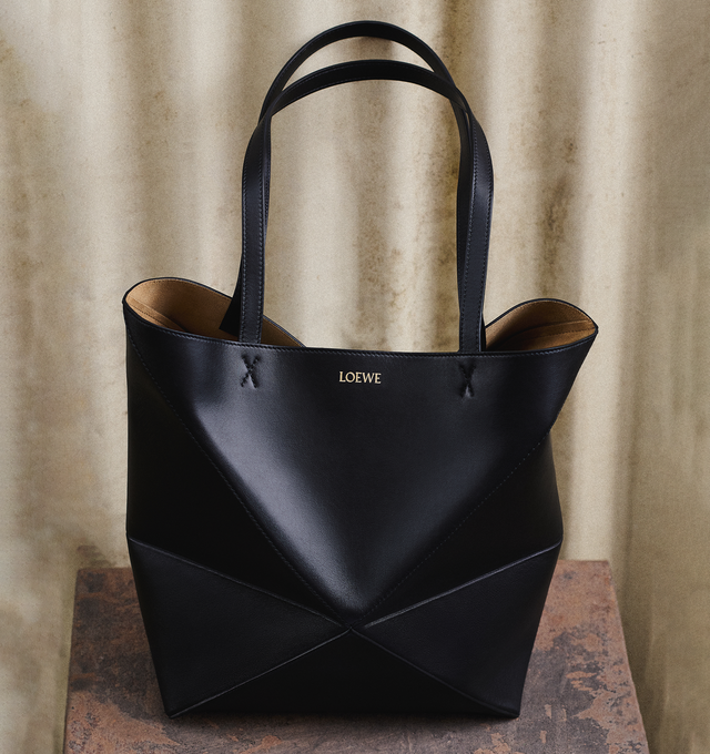 Image 6 of 6 - BLACK - LOEWE Mini Puzzle Fold Tote in shiny calfskin takes the iconic bags signature geometric lines and reimagines them in graphic and architectural panels that allow the bag to fold completely flat, making it the perfect travel companion. Soft, lightweight and inventively crafted, it is finished with discreet LOEWE branding. Features shoulder, crossbody or hand carry, detachable and adjustable strap, suede lining and gold embossed LOEWE. Measures 7.9" high X 6.5" wide X 3.7" deep with a 