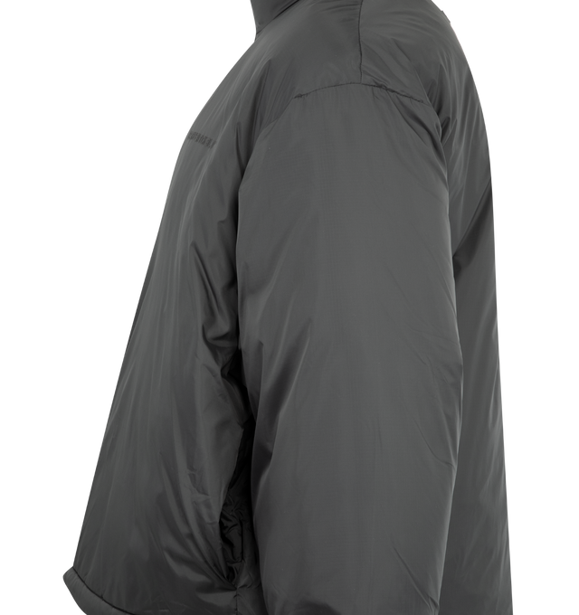 Image 3 of 3 - GREY - FEAR OF GOD ESSENTIALS Ripstop Nylon Puffer Jacket featuring ripstop nylon, matte appearance with water repellant properties, 3D Essentials  graphic on the chest, relaxed, rounded silhouette, high neck, side pockets, full zip front, elasticized piping on the cuffs and waist hem, bungee toggles at the waist hem for adjustable styling and a Fear of God Essentials rubberized label stitched at the back collar. 100% matte nylon. 