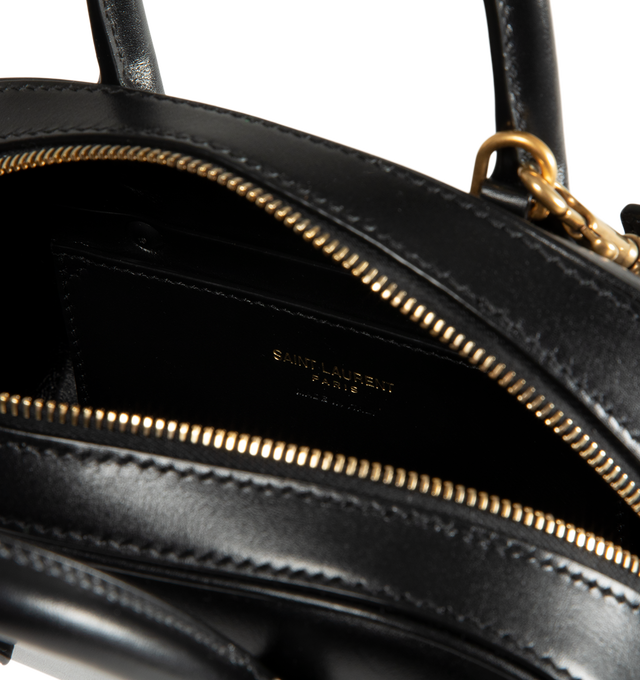 Image 3 of 3 - BLACK - Saint Laurent Womens Sac de Jour Mini Boston Bag is crafted from calfskin leather. Features top handles, adjustable and detachable shoulder strap, zip closure, leather lining, bronze-tone hardware, and two interior card slots. Dimensions: 19  13  7 cm; Handle Drop: 5 cm; Strap Drop: 45 cm. Main Material: Calfskin Leather; Hardware: Brass; Lining: Leather. Made in Italy. 