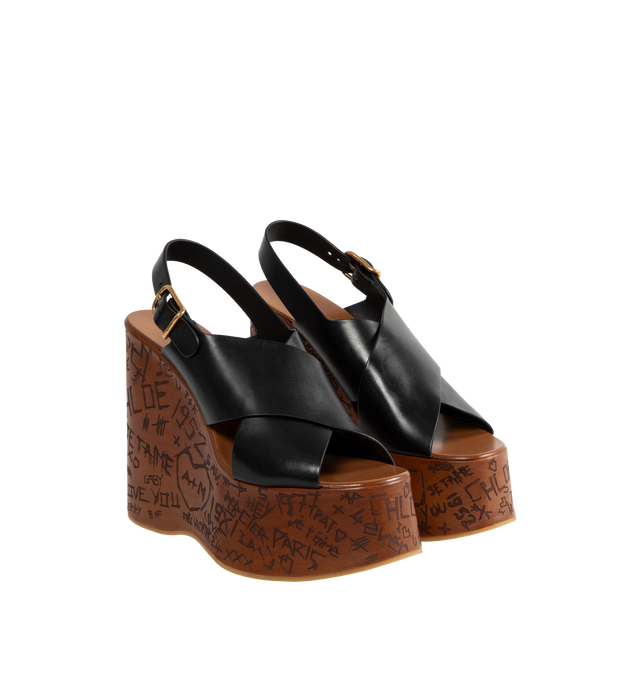 Image 2 of 4 - BLACK - CHLOE Maxime Wedges featuring criss-cross straps in semi-shiny cowhide with a wood-effect platform structure and Chlo-engraved buckle. 5.1" heel. Upper: semi-shiny cowhide. Inner sole: calfskin. Main lining: calfskin. Secondary lining: cowhide. Sole: thermoplastic polyurethane. 