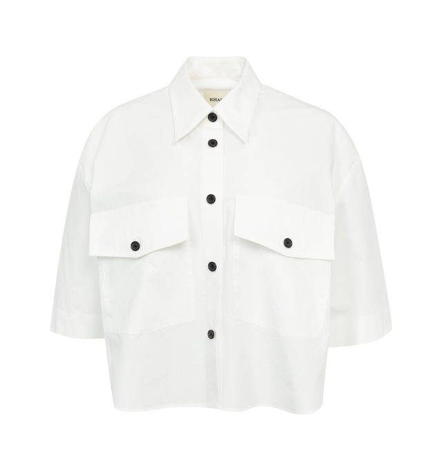 WHITE - KHAITE Mahsha Shirt featuring spread collar, short sleeves, front patch pockets, high-low hem and classic shirt style. 100% cotton.
