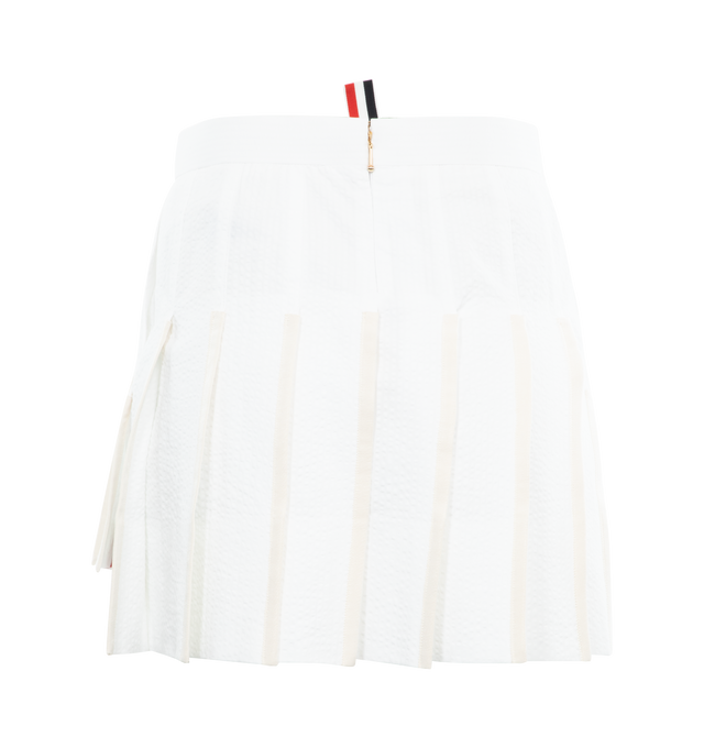 Image 2 of 3 - WHITE - THOM BROWNE Low Rise Mini Pleated Skirt featuring stiff cotton seersucker, back zip-up closure, signature grosgrain lined trim and signature grosgrain loop tab. 100% cotton. Made in Italy. 