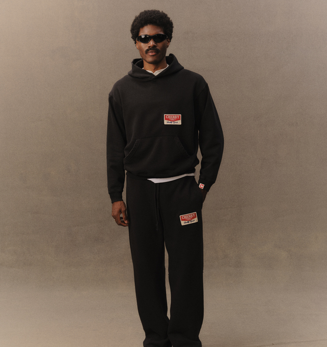 Image 4 of 6 - BLACK - Cherry LA Chevron Pullover Hoodie is crafted from custom cotton fleece and features a boxy-fit silhouette with a classic pullover design. Designed with a chest patch, distressed detailing, and a branded label at the cuff, this everyday essential combines a relaxed fit with Cherry LA's signature worn-in aesthetic. Main Material: Custom Cotton Fleece. Made in Los Angeles, California. 