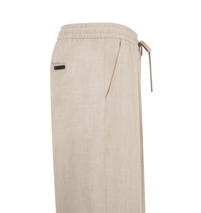 Image 3 of 3 - NEUTRAL - Fear of God Essentials Mens Pleat Front Drawstring Pants are crafted from cotton canvas. Feature a relaxed fit with a relaxed leg and seat, front pleats, elasticized waistband with heavyweight drawstring, side-seam pockets, back welt pockets, and an Essentials signature label. Main Material: 100% Cotton Canvas. 