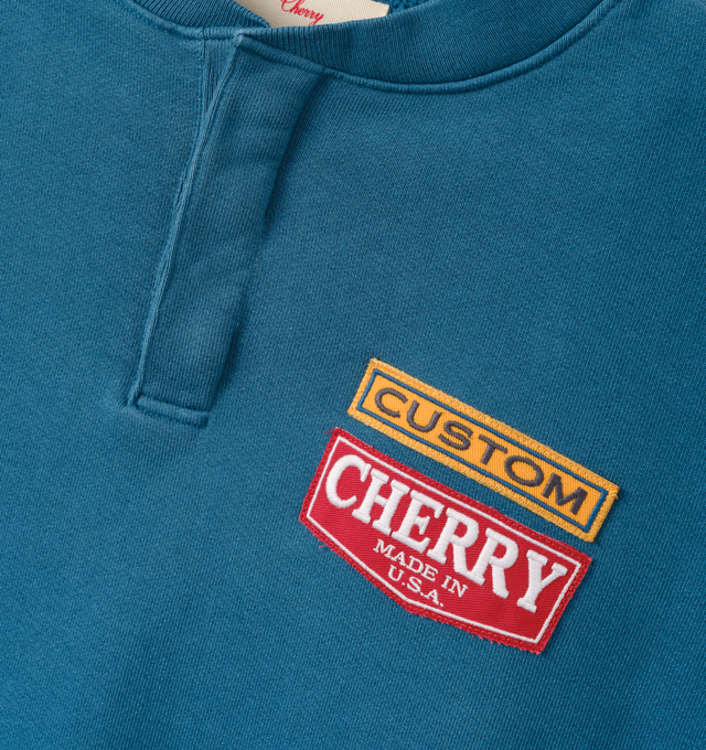 Image 3 of 7 - BLUE - Cherry LA Men's Patch Work Henley Crew is crafted from custom cotton fleece and features a boxy-fit silhouette with patchwork detailing at the chest and a concealed-button Henley placket. Designed for everyday comfort, this elevated sweatshirt is finished with hidden front buttons and a signature branded label at the cuff. Main Material: Custom Cotton Fleece. Made in Los Angeles, California. 