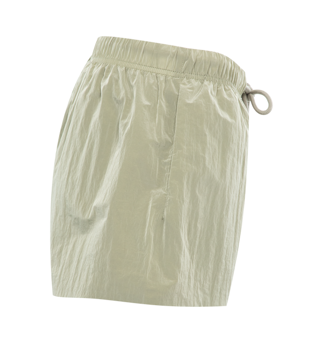 Image 3 of 3 - GREEN - FEAR OF GOD ESSENTIALS Crinkle Nylon Running Shorts featuring a relaxed fit, lightweight crinkle nylon construction, a rubber brand label on the front, side hand pockets, and an adjustable drawstring waistband. 100% nylon. 