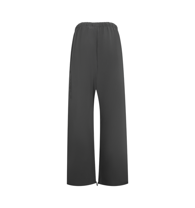 Image 2 of 3 - GREY - FEAR OF GOD ESSENTIALS Relaxed Track Pants featuring a drawstring waistband with long drawstrings, side hand pockets, wide leg openings with ankle zipper closures, seam details down the front legs, a silicone rubberized brand label on the front, a soft-touch Fear of God ESSENTIALS logo graphic down the leg and a baggy relaxed fit. 84% nylon, 16% spandex. 