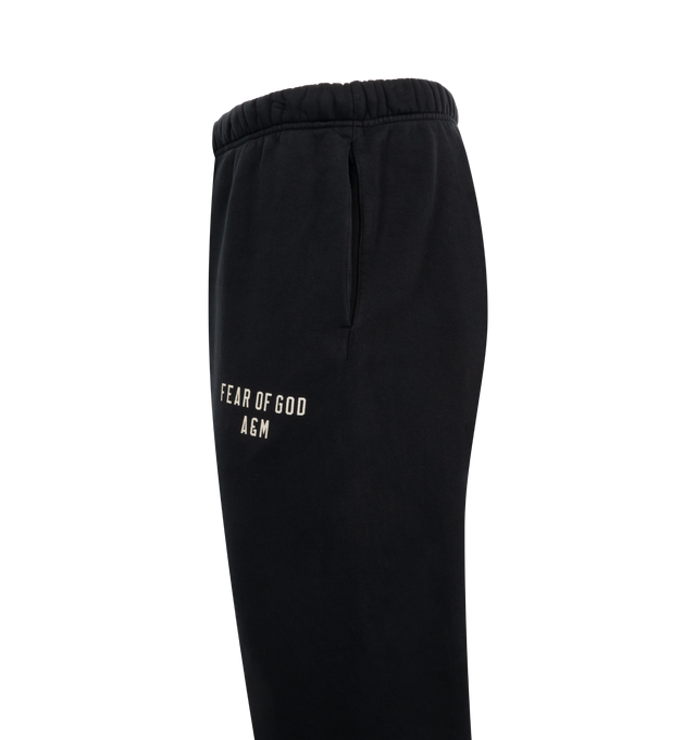 Image 3 of 3 - BLACK - Fear of God Essentials Heavy Fleece Sweatpants have an elastic drawstring waist, 3 stripe side panels, side pockets, elastic at the ankles, and a brand label. 83% cotton, 17% recycled polyester. 