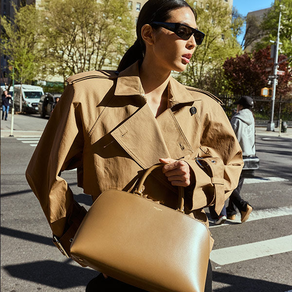 Woman carrying Saint Laurent Sac Du Jour duffle bag in brown leather