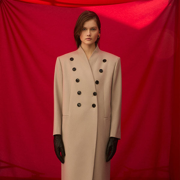 Woman wearing ALAIA Large beige wool coat featuring horn buttons in a v shape.