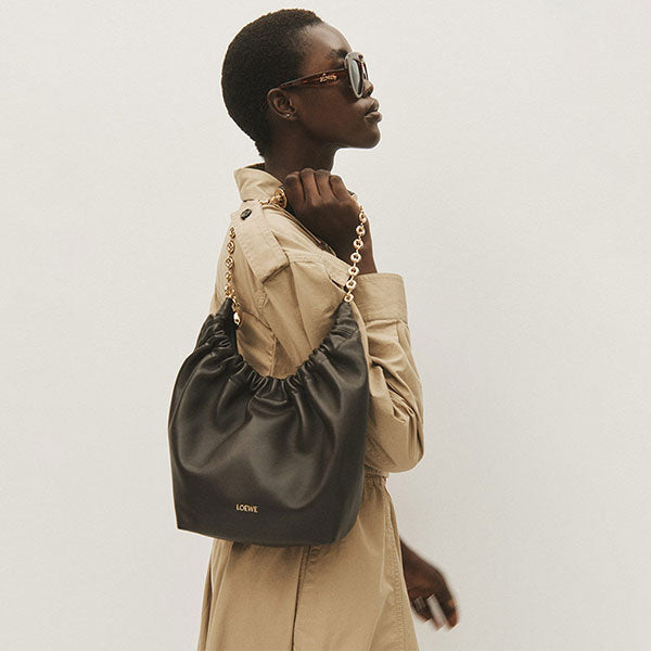 Woman wearing Bottega Veneta Twill Dress holding Loewe Squeeze Bag in olive leather