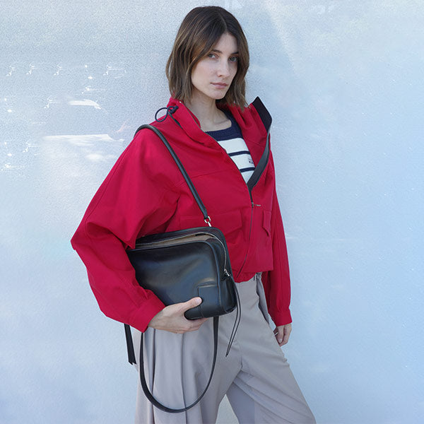 Woman wearing Loewe red jacket, striped sweater tee, holding Amazona 180 handbag