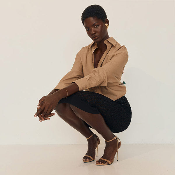 Woman in a beige shirt and black pencil skirt by Saint Laurent