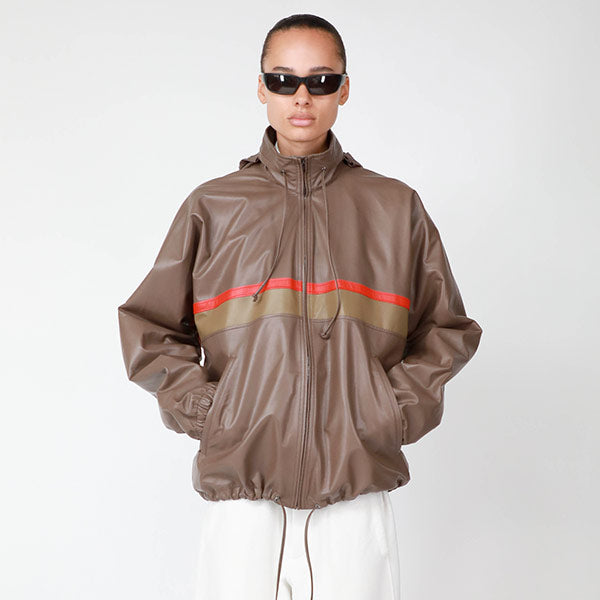 Woman wearing THE ROW Jilly Jacket in tan soft nappa leather with poppy red stripe and convertible hood 