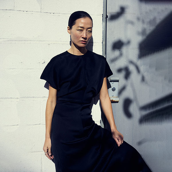 Woman wearing black dress by Toteme, available online.