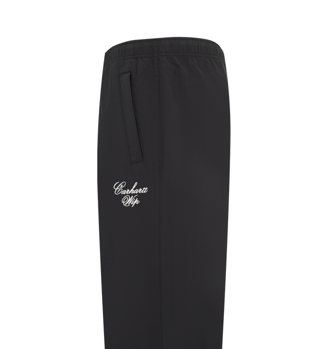 Image 3 of 3 - BLACK - Carhartt WIP Mens Travon Pants are crafted from lightweight nylon with a mesh lining and water-repellent finish. Feature an adjustable elasticized waistband, adjustable zipped leg openings, front and back zipped welt pockets, graphic embroidery, and woven flag label. Main Material: 100% Nylon. Made in Tunisia. 