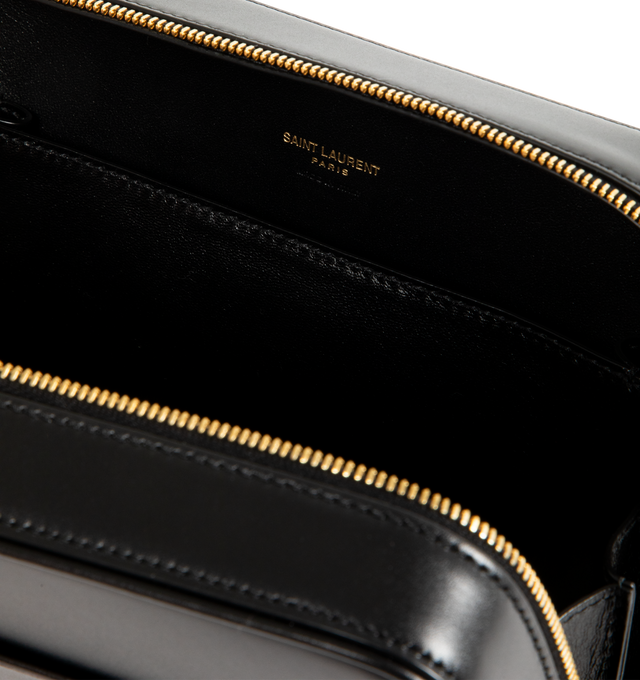 Image 3 of 3 - BLACK - Saint Laurent Men's small everyday case lined in tonal leather, featuring a flat front pocket with debossed SAINT LAURENT PARIS signature. An adjustable strap provides bespoke carry options. Featuring leather lining, bronze-tone hardware, two-way zip closure, one large flat pocket, one flat front pocket and adjustable strap. Measures 8.3" x 6.3" x 2.4" inches with 20.1" handle drop. Calfskin. Made in Italy. 