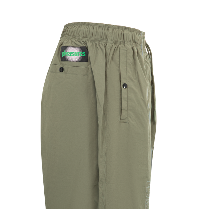Image 3 of 3 - GREEN - PLEASURES Sound Track Pant featuring piping detail, elasticized waist, relaxed fit, snap button front and back pockets, logo patch and full length. 100% nylon taslan. 
