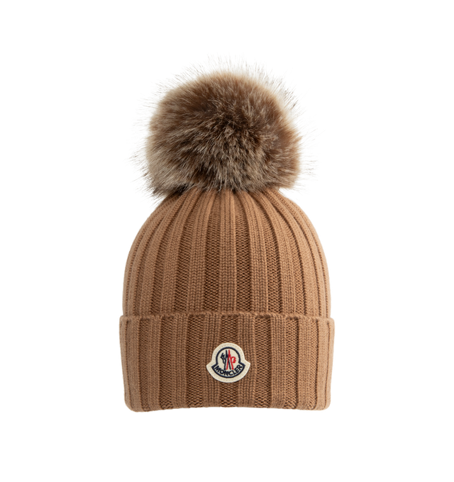 Image 1 of 2 - BROWN - Moncler Wool Beanie with Pom Pom features an English rib-knitting and logo at front and embellished with a faux fur pom pom. Designed to provide warmth, this heavy knit beanie for women adds the finishing touch to cold-weather looks. 100% virgin wool . 