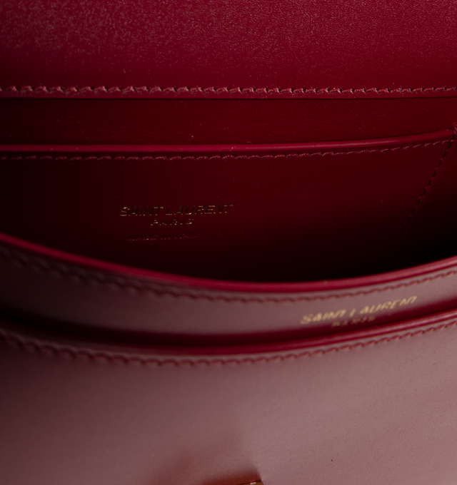 Image 3 of 3 - RED - SAINT LAURENT Mini Voltaire half-moon shoulder bag in calfskin with gently polished finish. Features a flap with magnetic Cassandre hinge closure and one flat interior pocket. Calfskin leather with leather lining and bronze-tone hardware. Made in Italy. Measures 8.3" X 4.3" X 1.8" with 9.4" strap drop.  