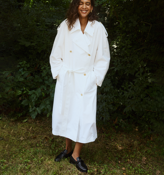 Image 4 of 4 - WHITE - THE ROW Denver Coat featuring calf-length, doubled-breasted trench coat in vintage cotton with raglan sleeves, buttoned shoulder epaulettes, removable belt, horn button closure, side welt pockets and removable liner. 100% cotton. Made in Italy. 