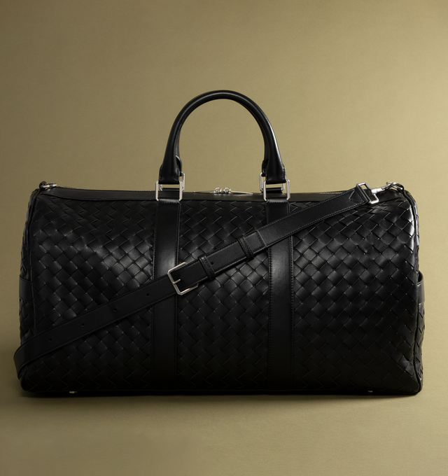 Image 2 of 4 - BLACK - Bottega Veneta Duffle bag in Intrecciato leather with adjustable and detachable strap. Featuring single exterior side zipped pocket, one interior zipped pocket, double flat open pockets, and zip closure.  Material: calfskin. Lining: Canvas. Hardware: Silver finish. Measures 11.4 high x 21.7 wide x 9.4" deep with 5.9" handle drop and 20.9 strap drop. Made in: Italy. 