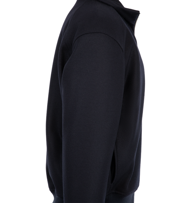 Image 3 of 3 - NAVY - Jil Sander Men's Padded Zip-Up Wool Jacket is crafted from technical faille and features a relaxed-fit silhouette with dropped shoulders, a stand collar, and a pack-away hood concealed within the collar. Designed for versatile everyday wear, this lightweight jacket is finished with a front zip closure, side welt pockets, a drawstring waist, elasticized cuffs, and a signature Jil Sander logo application at the sleeve. Main Material: Wool. Made in Italy. 