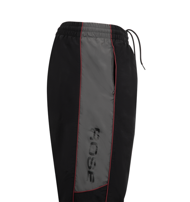Image 3 of 3 - BLACK - MARTINE ROSE Hockey Track Pants featuring loose fit, elasticated drawstring waistband, two side zip pockets, contrasting piping, embroidered logo at side and elasticated cuffs. 100% polyamide. 