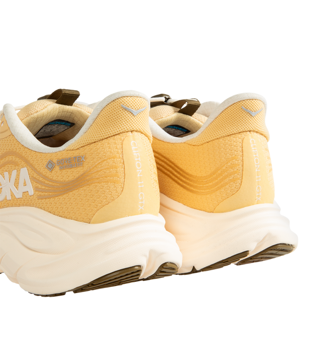 Image 3 of 5 - ORANGE - Hoka Women's Clifton 11 GTX Running Sneakers feature a closed-mesh upper with a GORE-TEX Invisible Fit membrane and PFC-free water-repellent treatment. An adjustable speed-lace system with toggle, reflective details, a compression-molded EVA midsole, and a Durabrasion rubber outsole with forefoot traction pods complete the weather-ready design. Upper: Mesh with GORE-TEX Membrane. Midsole: EVA Foam. Sole: Rubber. Heel-to-Toe Drop: 8 mm. 