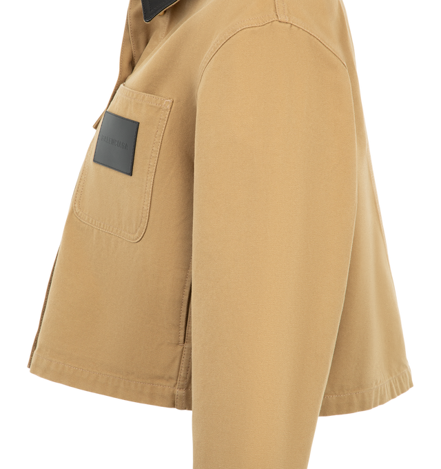 Image 3 of 3 - NEUTRAL - Balenciaga Women's Cropped Workwear Jacket is crafted from heavyweight cotton and features a cropped silhouette with a flat calfskin leather collar, a double-breasted five-button front, and gold-tone button detailing. Inspired by classic utility workwear, this designer jacket is finished with buttoned cuffs, a flap chest pocket, a patch pocket with a Balenciaga logo leather patch, and two front slash pockets, combining functional design with the house's modern aesthetic. Main Materi 