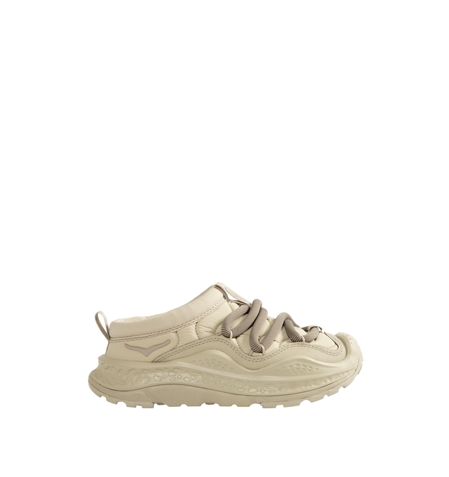 Image 1 of 5 - NEUTRAL - Hoka Unisex Ora Primo Sneaker featuring soft knit collar, insulated puff upper, slip-on style, zig-zag stitch detail, round elastic lace system and protective toe bumper. Nylon, textile. Rubber sole. *Unisex style in men's sizing.  