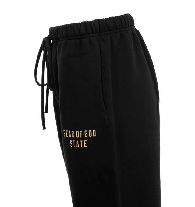 Image 3 of 3 - BLACK - Fear of God Fleece Sweatpants have an elastic drawstring waist, side seam pockets, elastic hems, and logo details. 83% cotton, 17% recycled polyester fleece.  