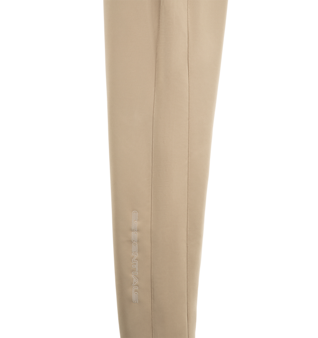 Image 4 of 4 - NEUTRAL - Fear of God ESSENTIALS Men's Classic Trackpant is crafted from heavyweight cotton-blend fleece and features a slim straight-leg silhouette with side-seam detailing and adjustable closure. Designed to provide structure and comfort, this elevated essential is finished with an encased elastic waistband, elongated drawcords, side-seam pockets, and an updated Fear of God Essentials label at the center front. Main Material: 80% Cotton, 20% Polyester Fleece, 380 GSM. Imported. 
