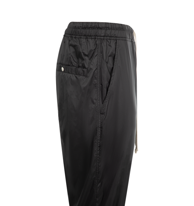 Image 3 of 3 - BLACK - Rick Owens Men's Tecuatl Track Pant crafted from black lightweight, fluid cupro twill. Full-length style with slightly dropped crotch, elasticized waist band with drawstring and stitched fly. Featuring 2 diagonal side front pockets, back welt pockets with snaps and elasticized hems with a zippered slit on the front shin.  100% Cupro, plant-based, biodegradable fabric made using repurposed cotton waste fibers. Buttons made from 100% buffalo horn. 