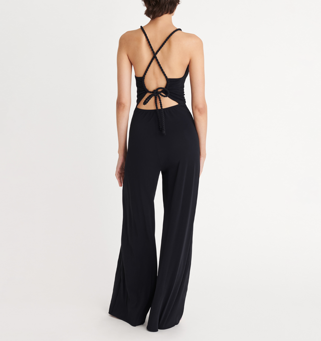 Image 4 of 5 - BLACK - ERES Donna Jumpsuit featuring sliding and twisted link to tie around the neck, adjustable straps crossed in the back, high neckline with shirring, open back and two side pockets. 94% Polyamid, 6% Spandex. Made in France.  