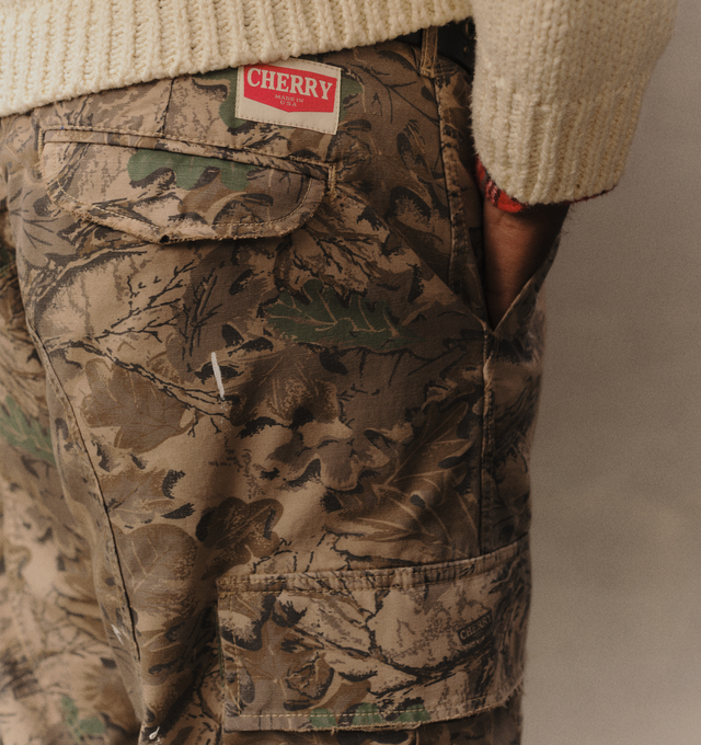 Image 7 of 7 - GREEN - Cherry LA Wide Leg Cargo Pants are crafted from custom camouflage cotton ripstop and feature a wide-leg silhouette with utility-inspired cargo pocket detailing. Designed with hidden snap closures at the pockets, paint splatter accents, and distressed finishes throughout, this statement style combines military influences with Cherry LA's signature lived-in aesthetic. Main Material: Custom Camouflage Cotton Ripstop. Fit: Wide Leg. Pockets: Cargo Pockets with Hidden Snap Closures. Detail 
