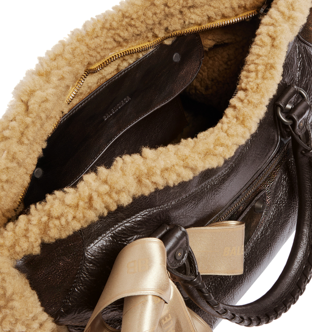 Image 4 of 4 - BROWN - BALENCIAGA Le City Bag Medium in brown calfskin and beige shearling, brass hardware featuring two leather hand-braided handles, adjustable and removable shoulder strap, ribbon with Balenciaga logo on the front, zipped closure with knotted leather puller, front zipped pocket with knotted leather puller, 1 inner zipped pocket and cotton canvas lining. 15.1" x 9.4" x 5.3". Calfskin, shearling, polyester. Made in Italy. 