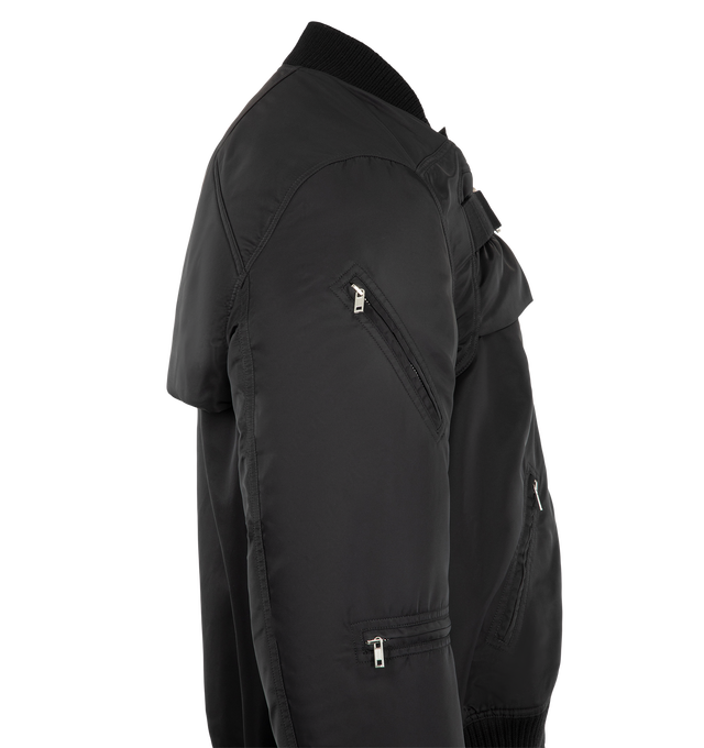 Image 4 of 4 - BLACK - Rick Owens Men's 2 Piece Flight Jacket is crafted from washed bomber satin and features a modular two-piece construction with a sleeveless zip-front body and detachable sleeve overlay. Designed with two vertical zip pockets, two diagonal front zip pockets, zipped forearm pockets, a diagonal upper-arm pocket, and a front strap with metal buckle detail, this runway style combines utilitarian functionality with the brand's signature experimental approach. Finished with rib-knit trims and 