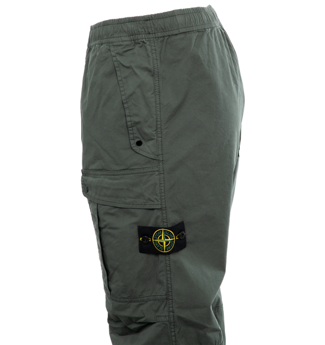 Image 3 of 4 - GREEN - STONE ISLAND Loose-Fit Cargo Pants featuring slanting hand pockets with slanted shaped flap and snap fastening, one patch bellows pocket on the back with shaped flap fixed on one side with a snap on the other side, big patch bellows pocket on the left leg, fixed on one side, snap on the other side, Stone Island badge, elasticized leg bottom and elasticized waistband with inner drawstring. 97% cotton, 3% elastane/spandex. 